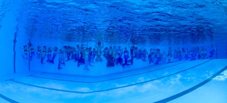 a group of people swimming in a pool mermaids gruppe von meerjungfrauen