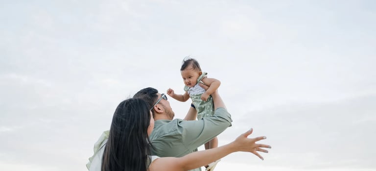 Mother lifting her daughter with the ocean in the background during a family photography session in Bali.