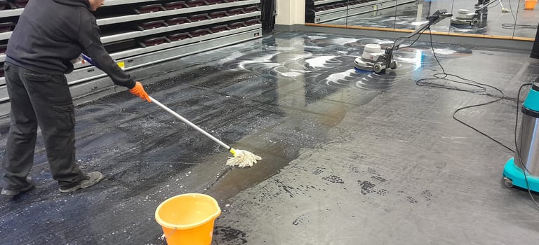 a man is cleaning a floor with a broom and bucket