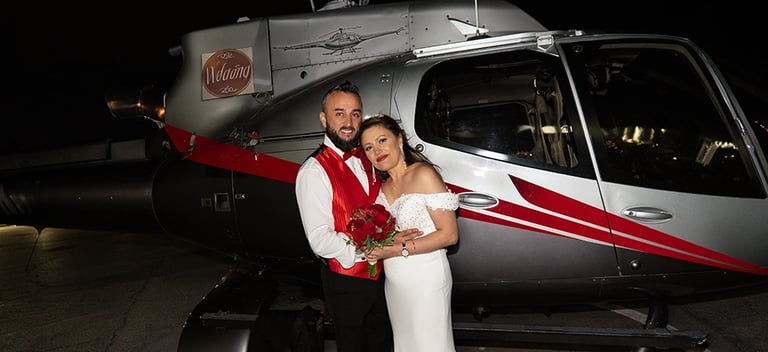 bride and groom taking photos by a helicopter