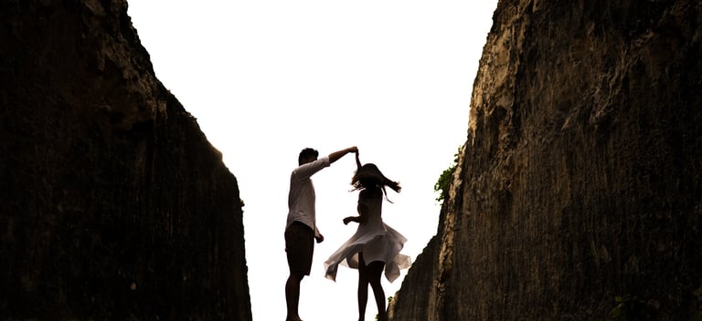 Silhouette couple proposal between cliffs at Melasti Beach Bali during sunset