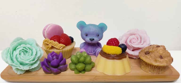 a wooden tray with a teddy bear, cupcakes and flowers made from soap