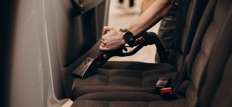Nettoyage de la banquette arrière d'une voiture avec un aspirateur.