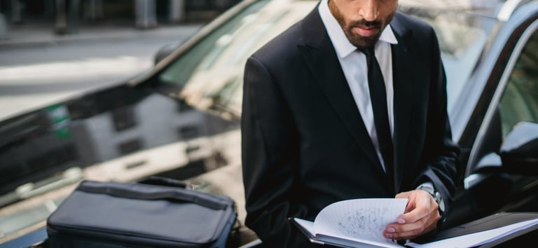Expert assis sur le capot de sa voiture, travaillant pour aider ses clients à vendre leur véhicule.