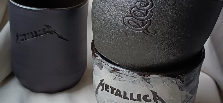 Juodi puodeliai su Metallica simbolika