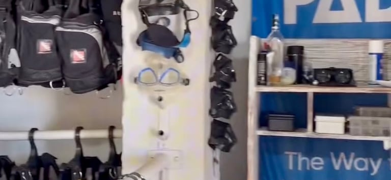 Scuba diving rental shop featuring PADI signs, snorkeling masks, and BCD jackets on racks.