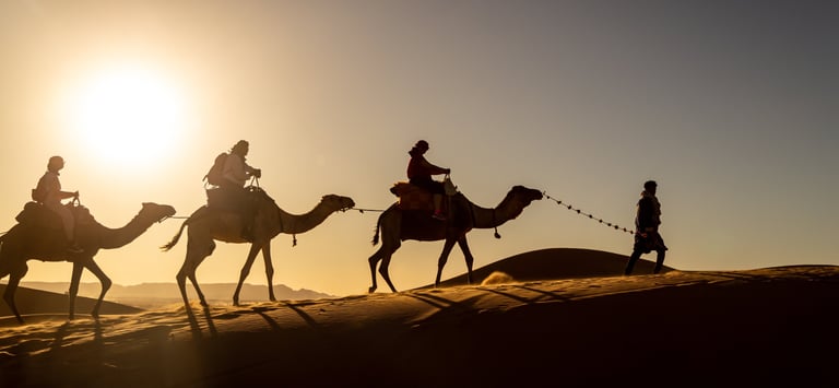 a group of people riding camels in the desert