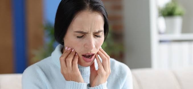 Women touching her jaw in pain, showing symptoms of TMJ disorder.