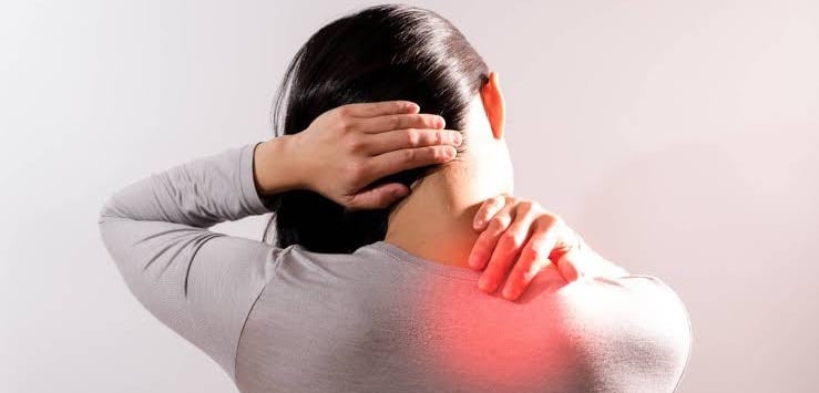Person holding back of neck in pain due to muscle stiffness.