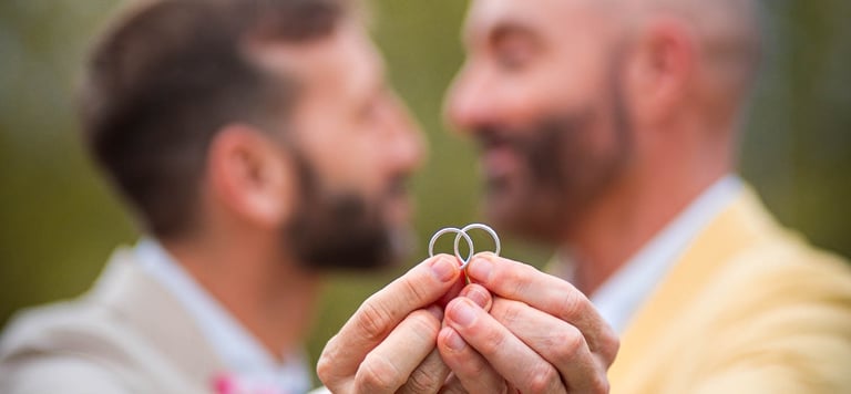 "Pareja gay casada mostrando sus anillos de boda en Madrid, celebrando su amor y unión."