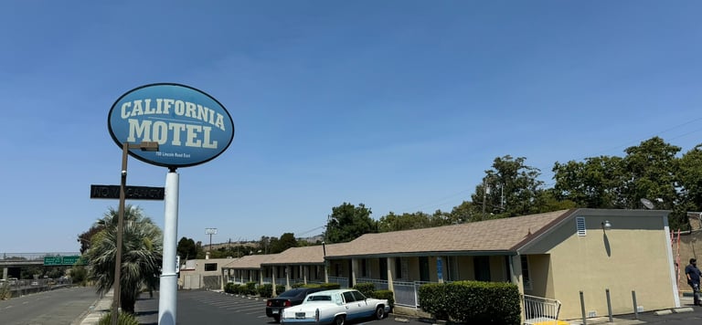a motel sign that says california motel with the motel in the background and a blue sky