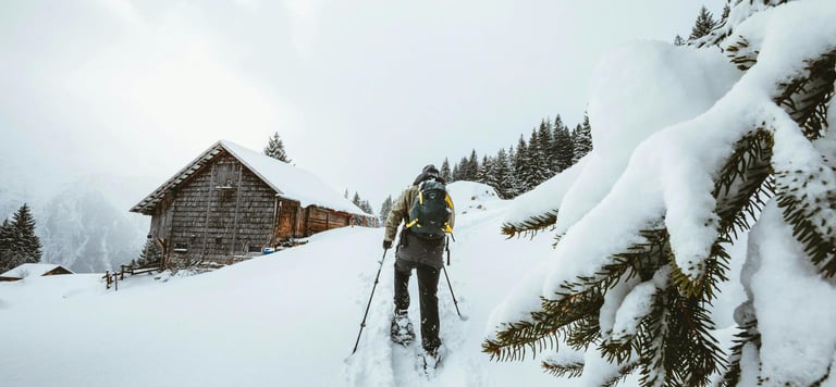 persona caminando en al nieve con cabaña de fondo
