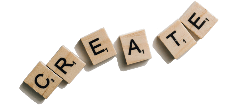 Wooden Scrabble tiles spelling out the word "CREATE" diagonally on a light-colored background.