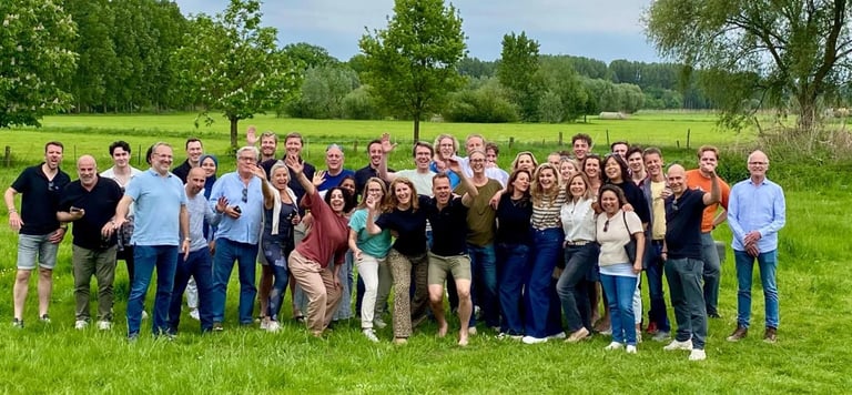 Groepsfoto van enthousiaste deelnemers tijdens Talenttrainer evenement in groene landelijke omgeving
