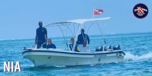 Scuba Duka diving boat carrying divers across the blue ocean water in Diani Beach, Kenya.