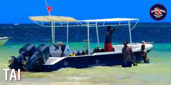 Scuba diving boat Tai by Scuba Duka Diani Beach Kenya with divers in turquoise ocean water.