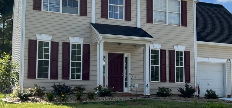 After overgrown shrubs were removed smaller shrubs were installed and windows of house are now visible.