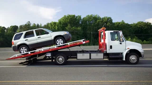 <img src="junk-car-tow-truck-loading.jpg" alt="Tow truck loading a silver SUV for junk car removal o