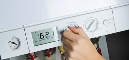 control dial on a modern white combi boiler to adjust the home heating temperature.