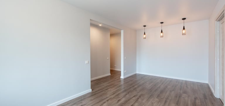 Modern room with hardwood flooring and white baseboards.