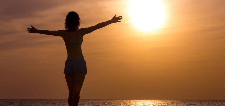 femme libre et heureuse et sereine qui regarde l'horizon en levant les bras