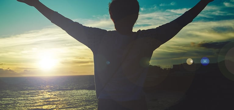 homme levant les bras face au soleil. nouveau depart grace au magnetisme