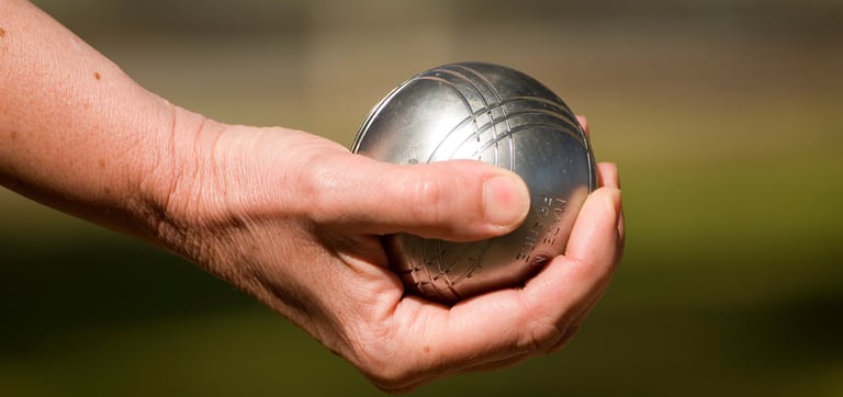 une main tient une boule de pétanque