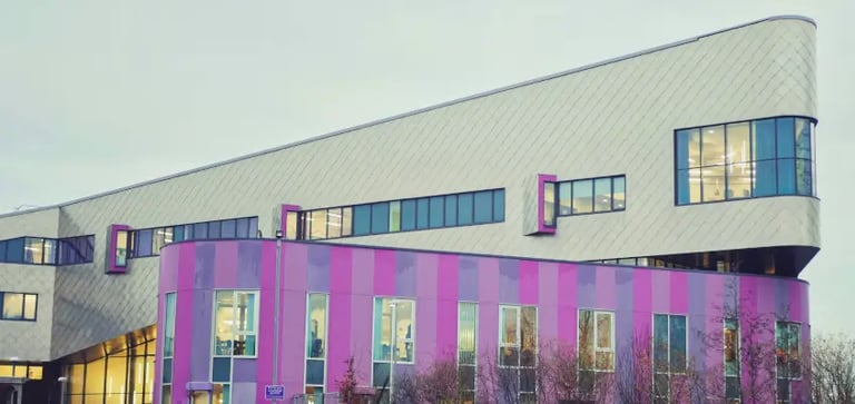 a modern academy school with sharp lines in a triangular shape with purple ground floor.