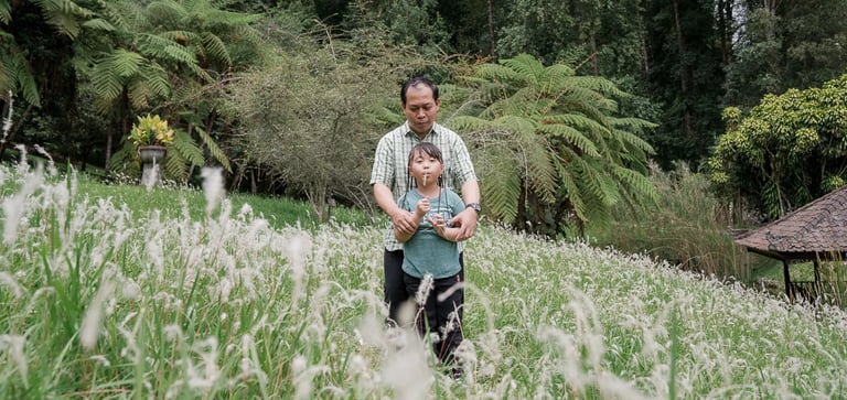 Father and son walking through a scenic grass field during a family photography session in Bedugul Bali.