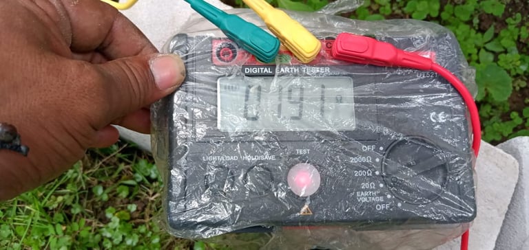 A digital earth tester meter displaying a resistance reading with color-coded test leads attached.