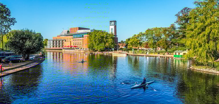 a photo of the Royal Shakespeare Theatre at Stratford Upon Avon with the river Avon in the foreground