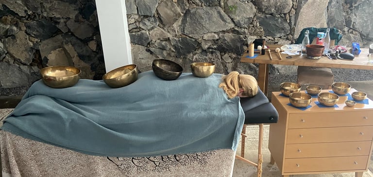 a person laying down covered with sound bowls
