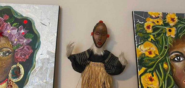Handcrafted African tribal doll, dressed in a straw skirt, presented between two hybrid paintings by