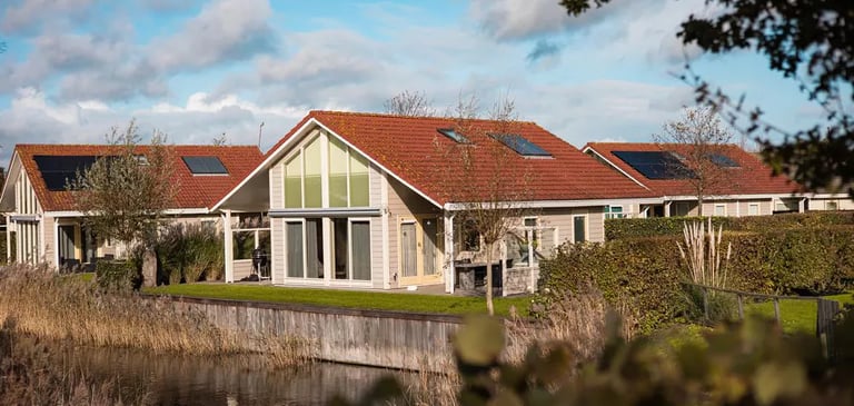  Luxuriöse Ferienhaus in einem Ferienpark direkt am Wasser mit Solaranlage und rotem Ziegeldach.