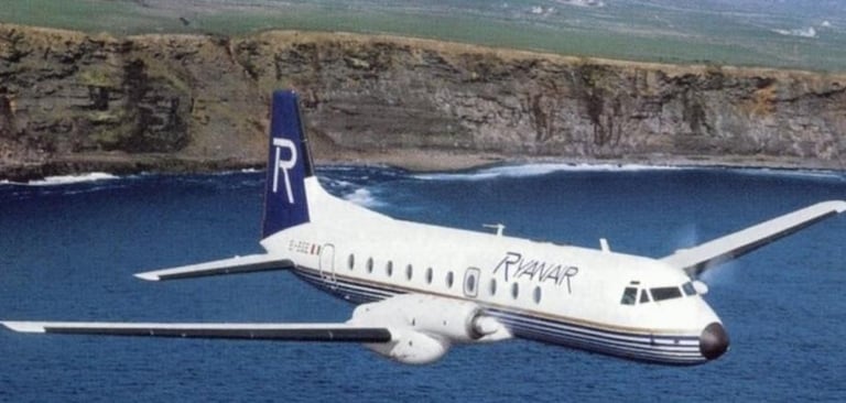 Vintage Ryanair propeller airplane flying over the ocean near steep coastal cliffs.