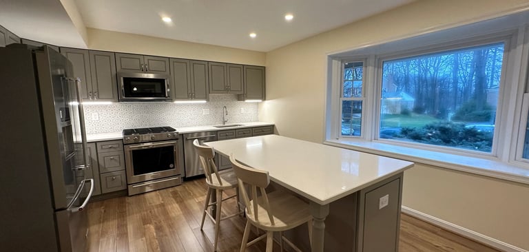 A beautifully updated kitchen featuring gray shaker cabinets, quartz countertops, and warm LVP