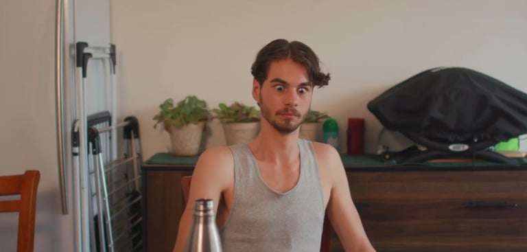 a man sitting at a table with a bottle of beer