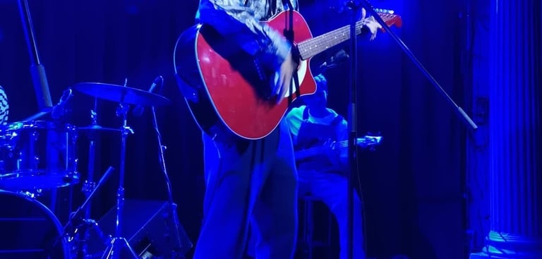 Olly Williams Brighton UK live musician performing with red guitar under stage lights