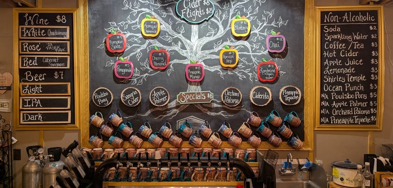 A chalkboard bar menu featuring cider flights, wine, beer, and non-alcoholic drinks above a row of tap handles.