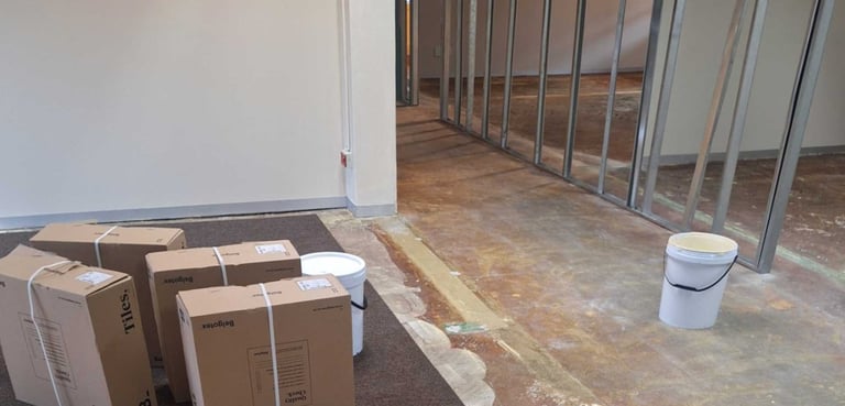 Office interior in early renovation phase with floor preparation and drywall framing.