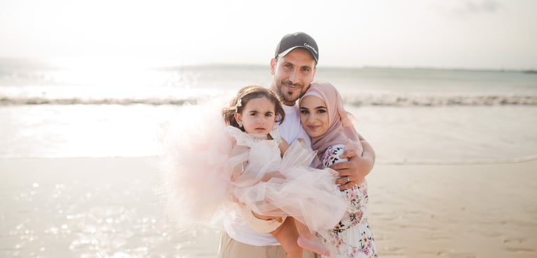 family photography Jimbaran Beach Bali parents holding child by the sea