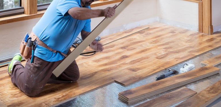homem trabalhando colocando um piso de madeira laminado