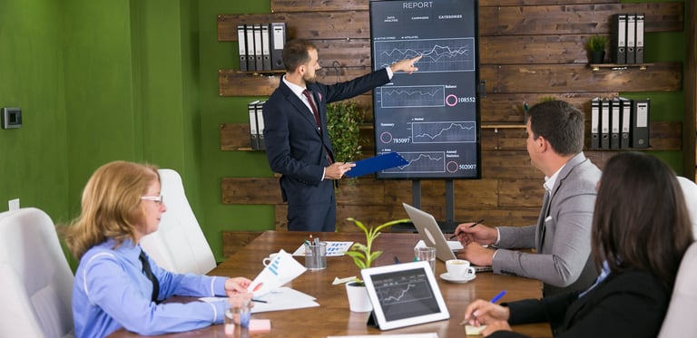 Man presenting a digital chart about Digital AI Marketing to his team in an office