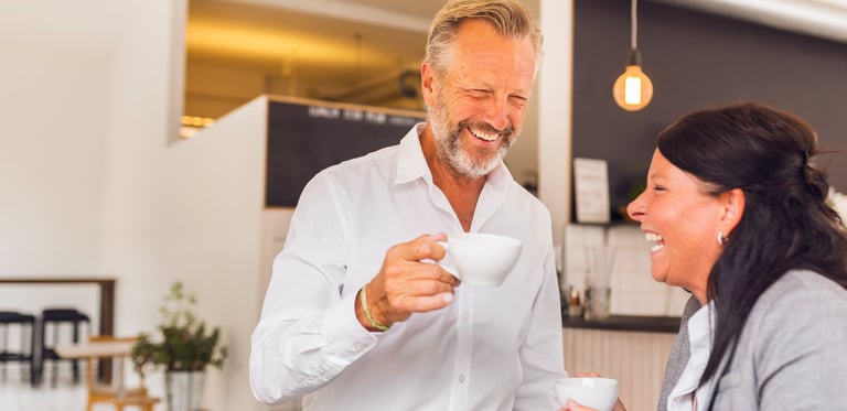 Two office colleagues drinking coffee and laughing