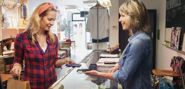 Women pays with her mobile in a shop, illustrating a good customer engagement