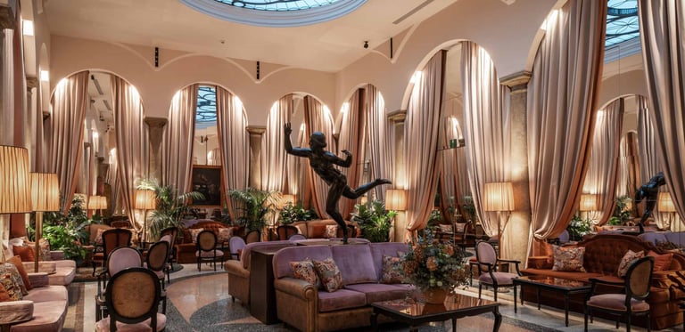 Elegant luxury hotel lounge with plush velvet seating, marble floors, and a decorative glass skylight.