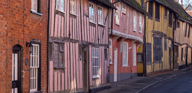 Historic timber-framed medieval houses in Lavenham, Suffolk, featuring colorful plaster facades.