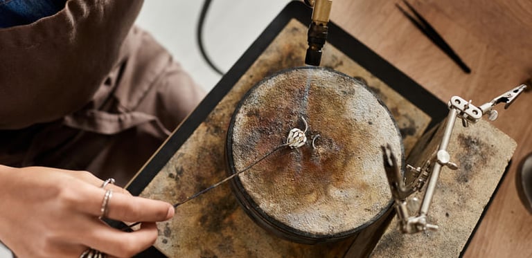 Joyero usando un soplete para soldar un anillo de plata sobre un bloque de soldadura en un taller