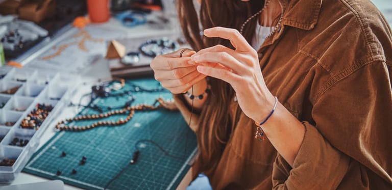 Artesana elaborando joyería hecha a mano en su mesa de trabajo.