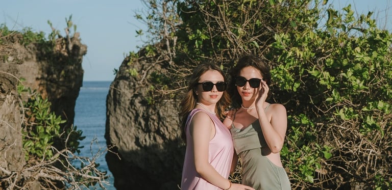 Two friends posing together on rock cliff during photoshoot at Geger Beach Nusa Dua Bali